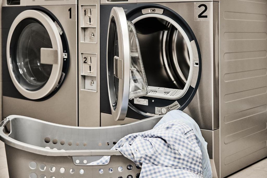 a laundry room with three washing machines and a washer and dryer at GRONERS Leipzig City Center in Leipzig
