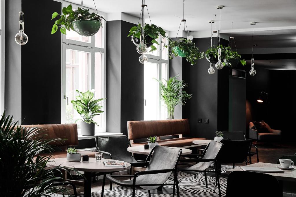 a restaurant with tables and chairs and potted plants at GRONERS Leipzig City Center in Leipzig