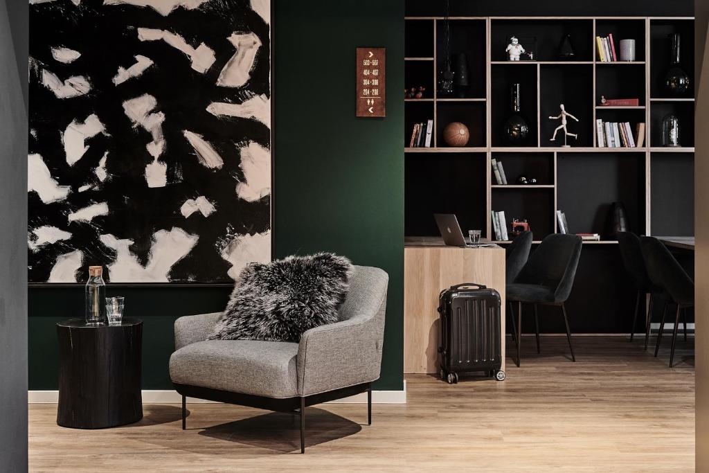 a living room with a chair and a desk at GRONERS Leipzig City Center in Leipzig