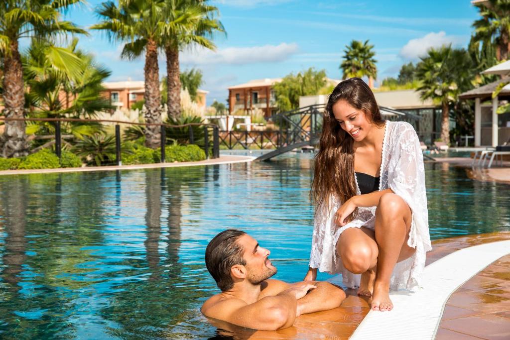 a man and a woman sitting in a swimming pool at Monte Santo Resort in Carvoeiro
