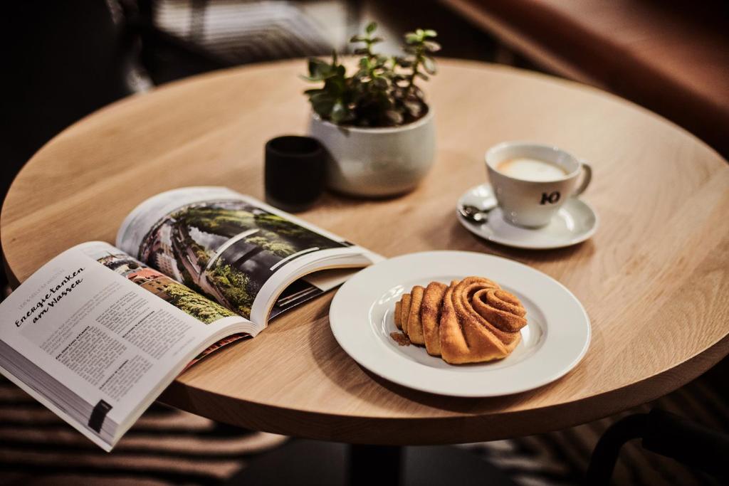 a table with a book and a plate of food and a cup of coffee at GRONERS Leipzig City Center in Leipzig