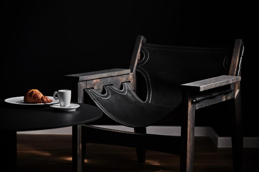 a chair and a table with a cup of coffee and a pastry at GRONERS Leipzig City Center in Leipzig