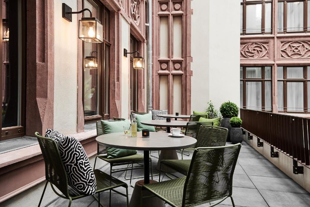 a patio with tables and chairs and windows at GRONERS Leipzig City Center in Leipzig
