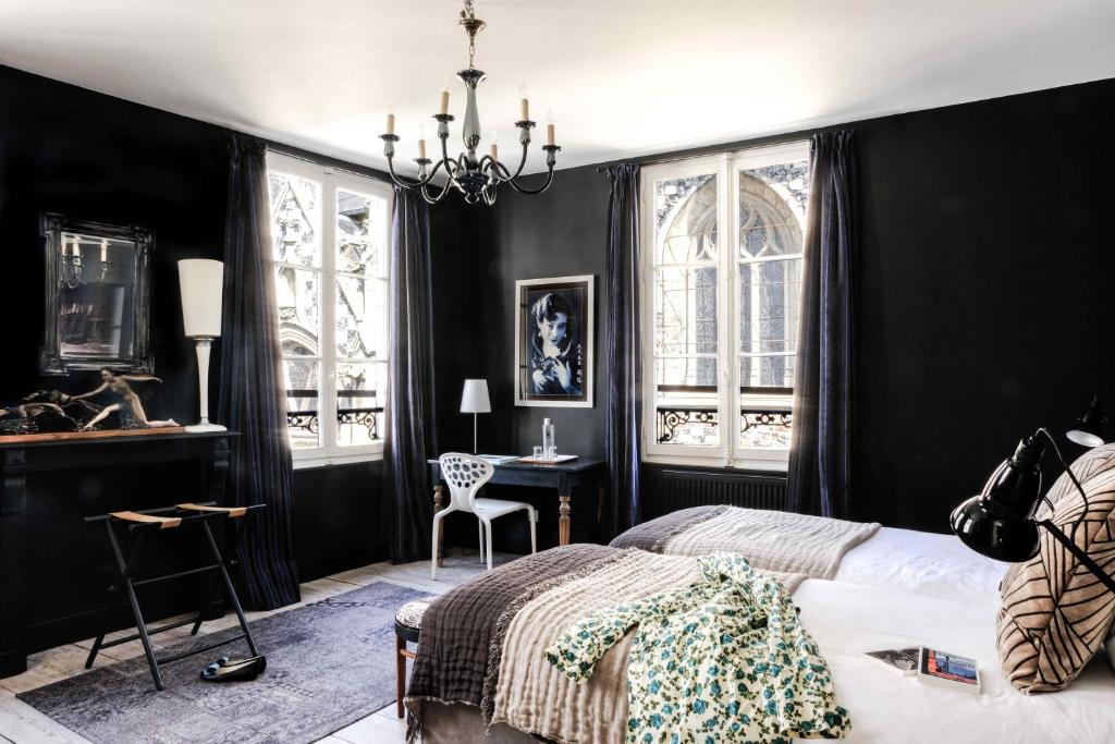 - une chambre avec des murs noirs, un lit et un bureau dans l'établissement Au Velocipede, à Saint-Valery-sur-Somme