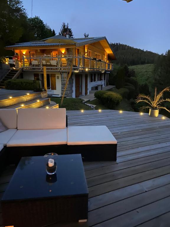 ein Haus mit einer Terrasse mit weißen Möbeln und Lampen in der Unterkunft Appartement de montagne au Chalet de Snow in Xonrupt-Longemer