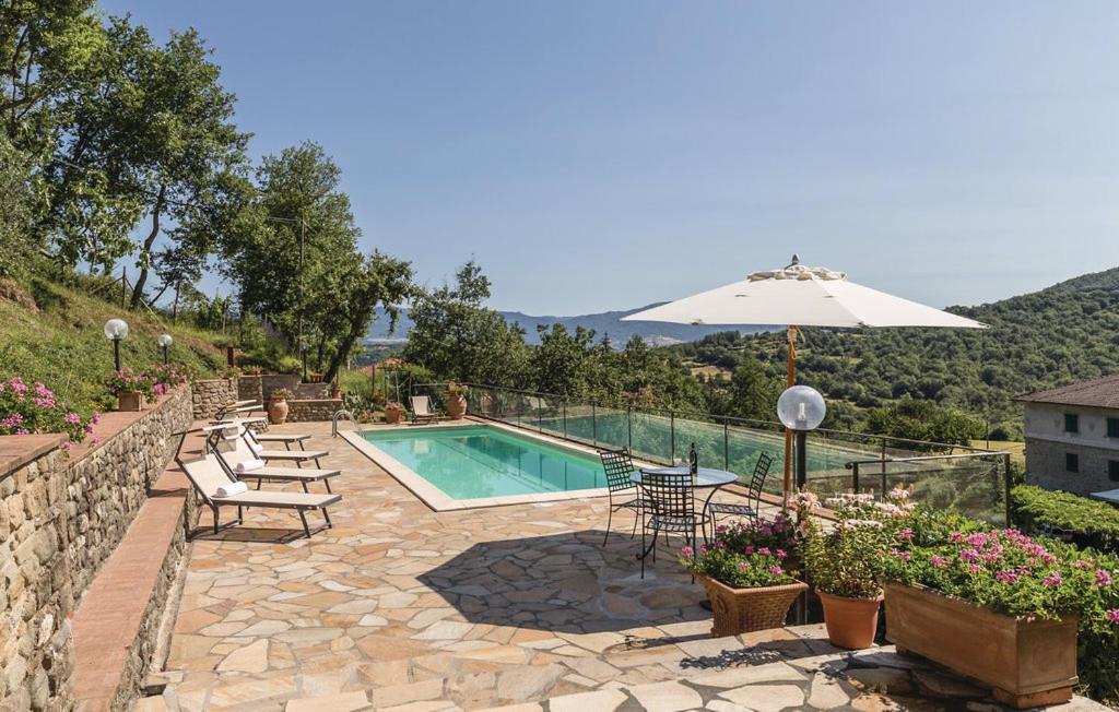 a swimming pool with an umbrella and chairs and a patio at Villa Silvana in Ortignano Raggiolo