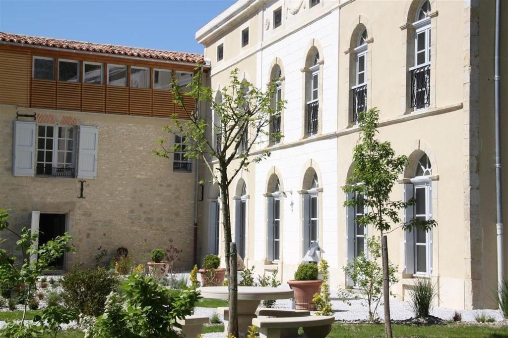 un edificio con un árbol delante de él en Le Gîte du Château, en Auriac-sur-Vendinelle