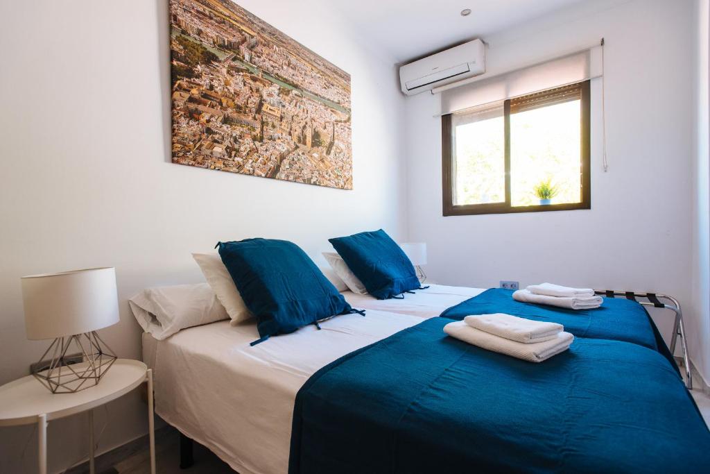 a bedroom with two beds with blue sheets and a window at Hostly Plaza de Armas Lightfull loft-Center-Parking op-CLess in Seville