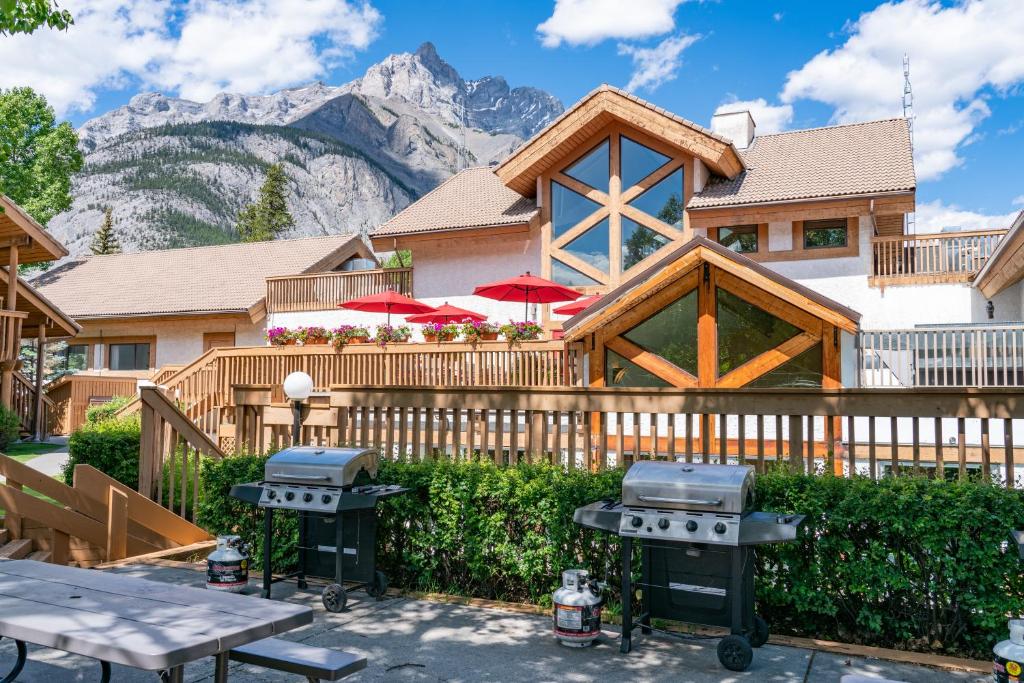 a house with a grill and mountains in the background at Banff Rocky Mountain Resort in Banff