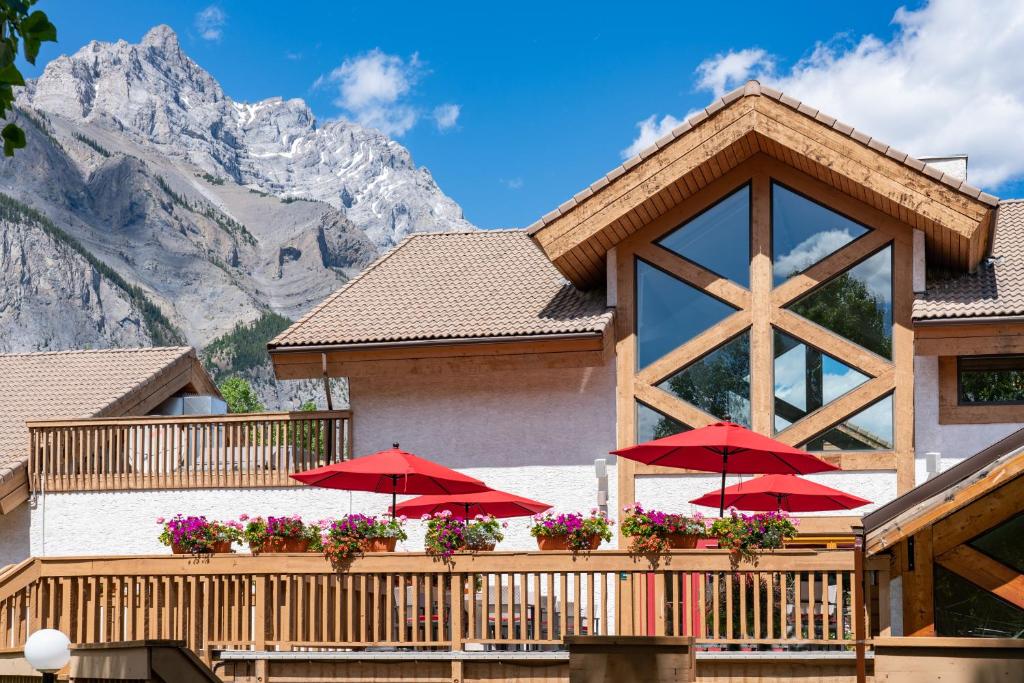 a house with red umbrellas in front of a mountain at Banff Rocky Mountain Resort in Banff
