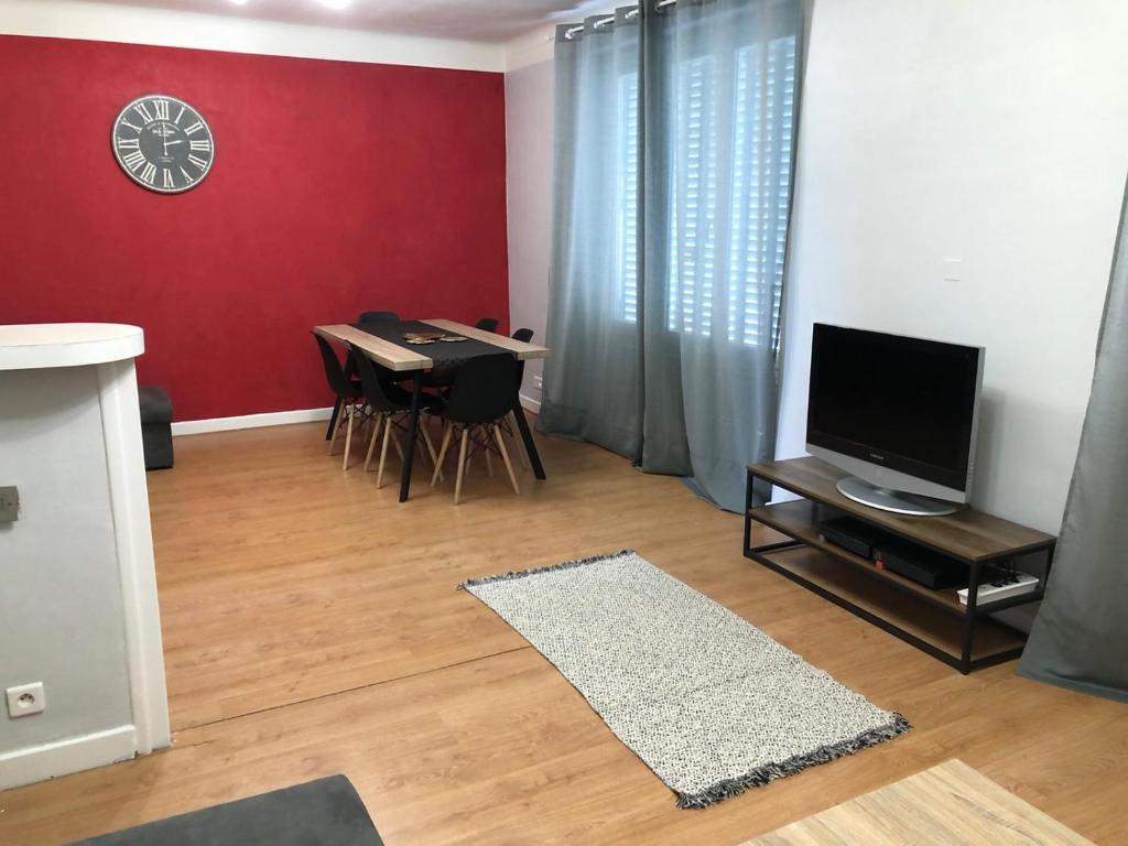 Il comprend un salon doté d'une télévision et d'une table avec des chaises. dans l'établissement Monfs Apparts Clermont-Ferrand, pres de toute commodites, à Clermont-Ferrand