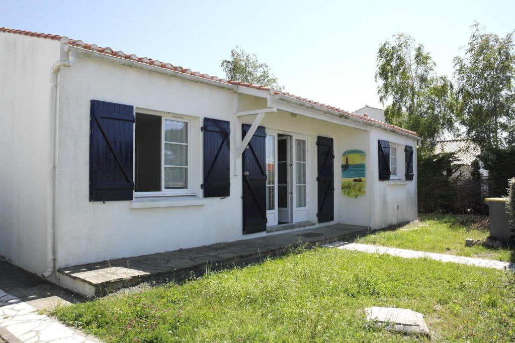 a white house with blue windows and a yard at Maison pour 6 au coeur de Saint-Hilaire-de-Riez in Saint-Hilaire-de-Riez