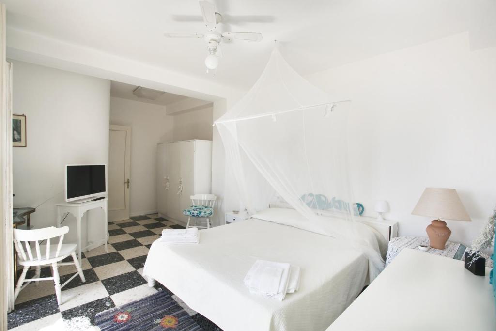 - une chambre blanche avec 2 lits et une télévision dans l'établissement villa stella del mare, à Acireale