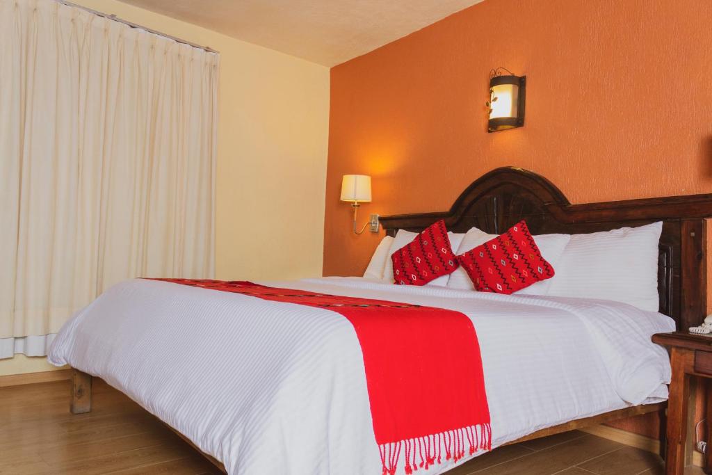 1 dormitorio con 1 cama grande con almohadas rojas y blancas en Plaza Magnolias en San Cristóbal de Las Casas