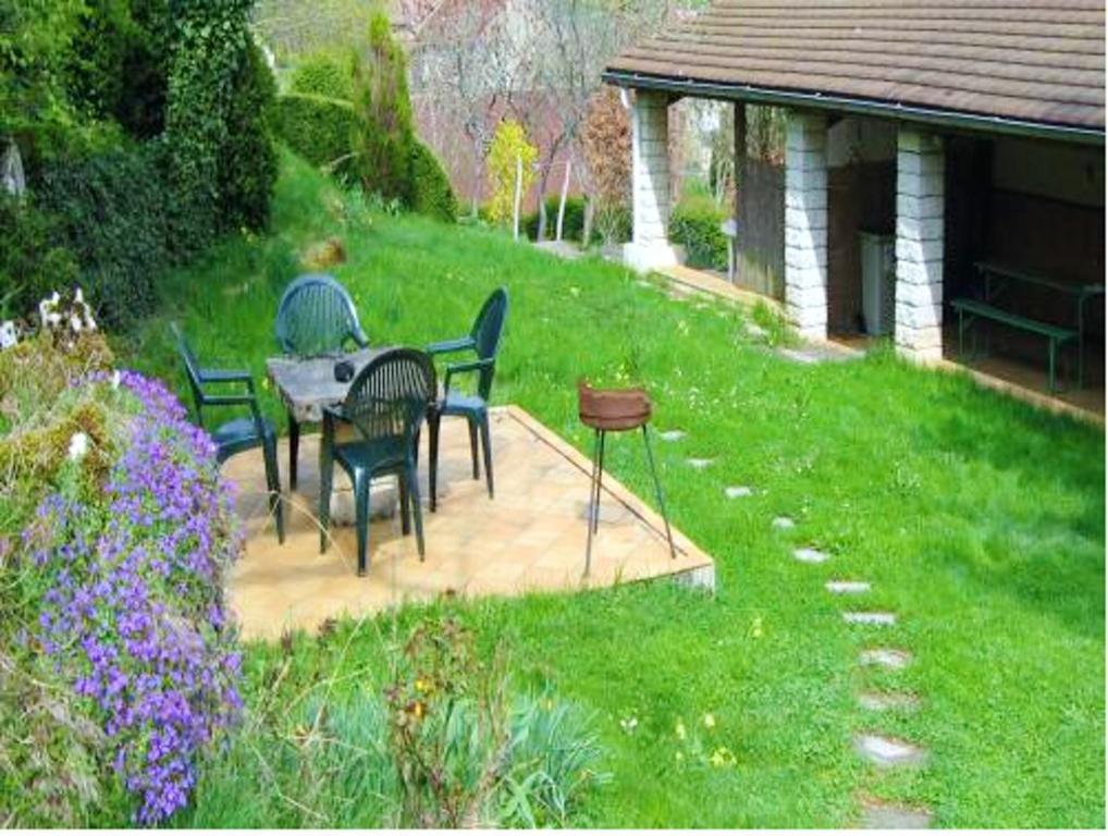 a person sitting at a table in a garden at Maison de charme à Saint-Laurent-la-Roche avec jardin clôturé in Saint-Laurent-la-Roche