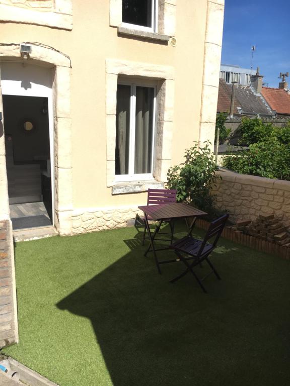 a patio with two chairs and a table on the grass at Le 21 TER in Amiens