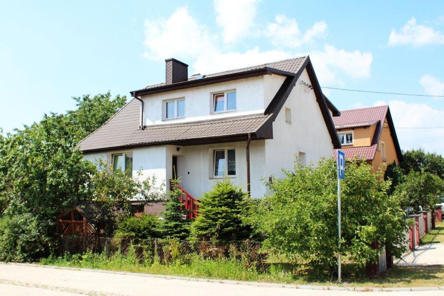 ein weißes Haus mit schwarzem Dach auf einer Straße in der Unterkunft Pokoje u Gabi in Bytów