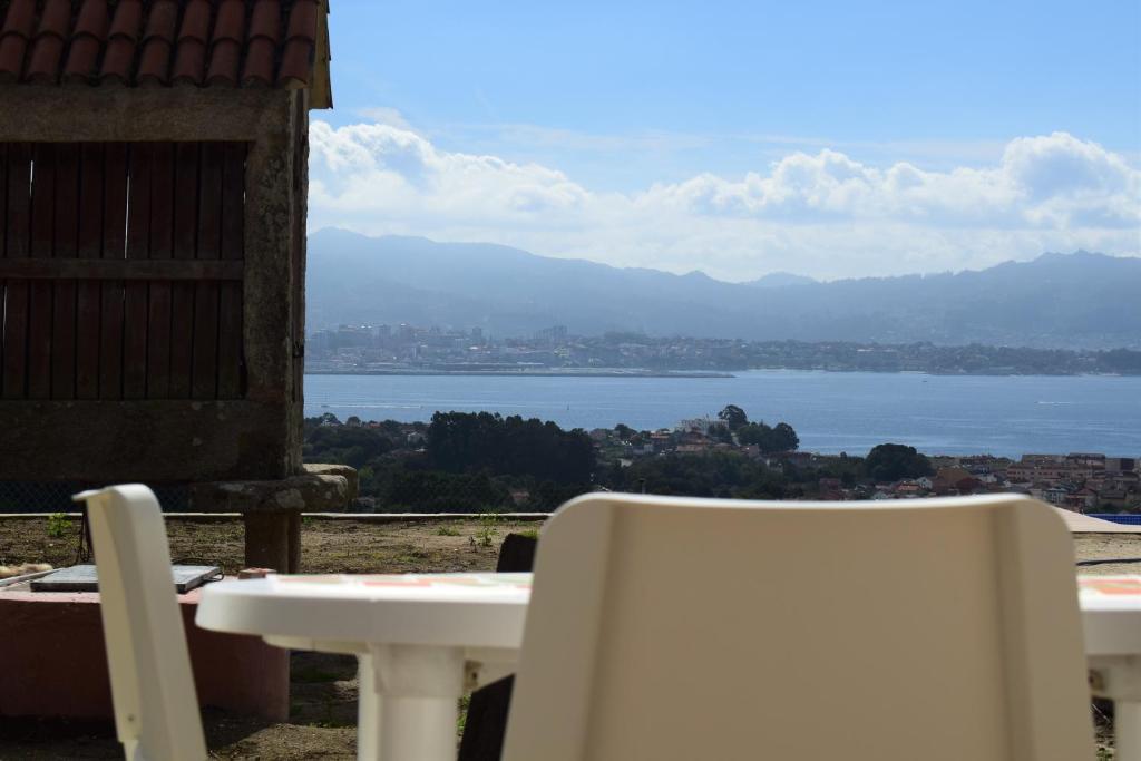 a table and chairs with a view of the water at Pedra da Lan - una casita de piedra in Cangas de Morrazo