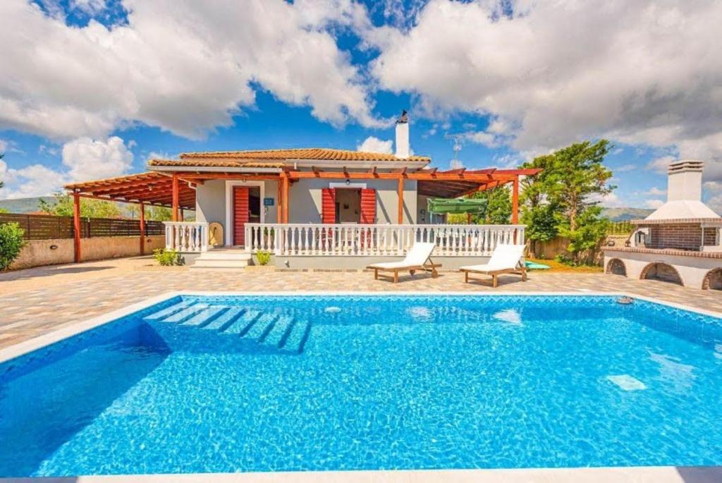 a villa with a swimming pool in front of a house at Pothos Villas in Zakynthos Town