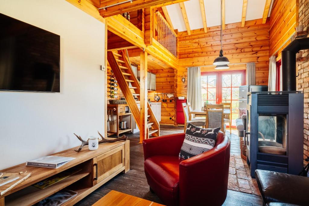 a living room with a red chair and a fireplace at Blockhaus an der Skiwiese Braunlage in Braunlage