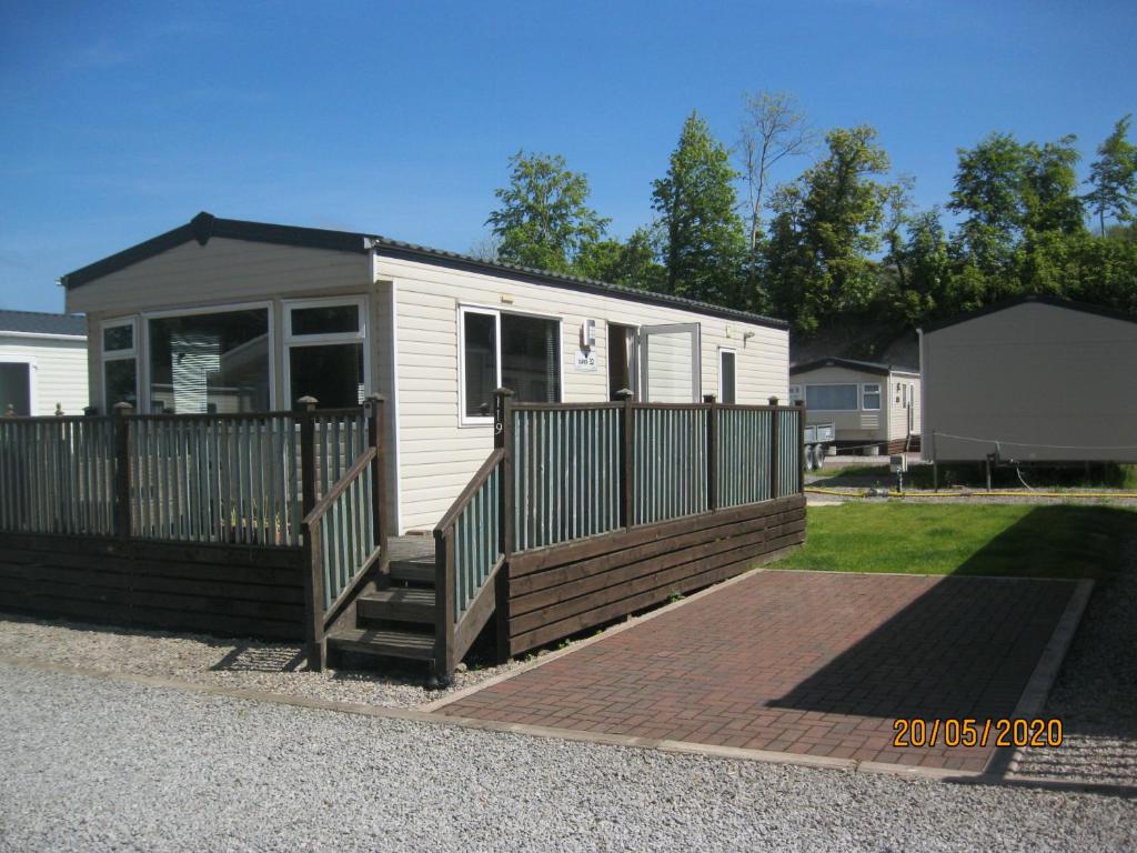 a tiny house with a porch and a deck at 119 Brigham Holiday Park. in Cockermouth