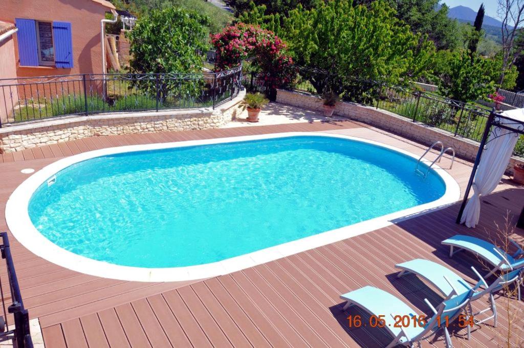 une piscine sur une terrasse en bois avec des chaises autour dans l'établissement Maison charmante à Gargas avec piscine privée., à Gargas