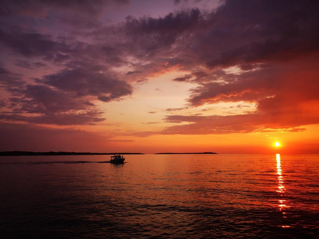 - un bateau sur l'eau au coucher du soleil dans l'établissement Holiday house Pineta - Fazana, sea view & mini wellness, à Fažana