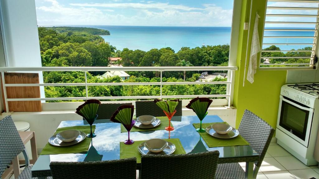 - une salle à manger avec une table et une vue sur l'océan dans l'établissement Appartement d'une chambre avec vue sur la mer piscine partagee et balcon amenage a Sainte Anne a 1 km de la plage, à Sainte-Anne