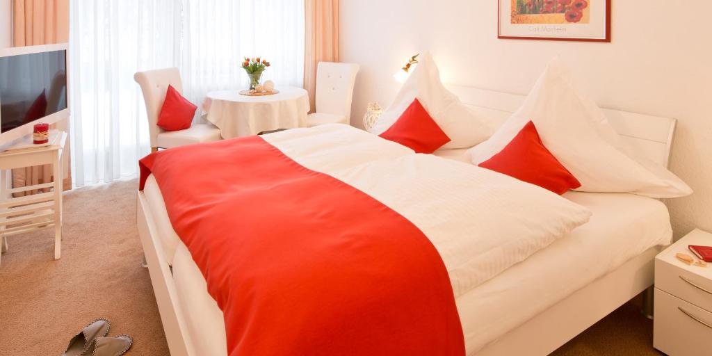 a red and white bed in a room with a table at Pension Gimpel in Bad Wildungen