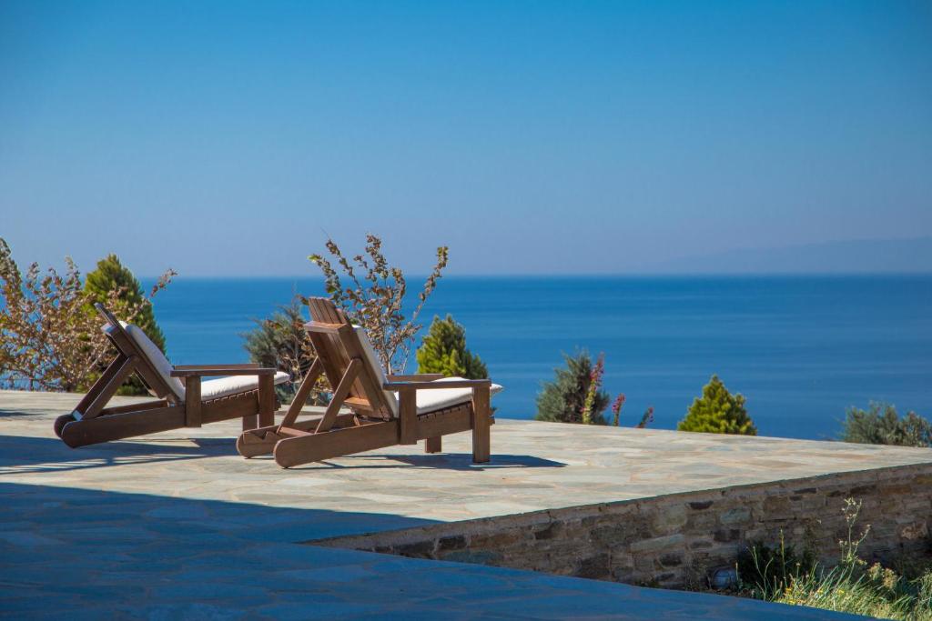 2 Holzstühle auf einer Terrasse mit Meerblick in der Unterkunft Eleni's Guesthouse in Apróvaton