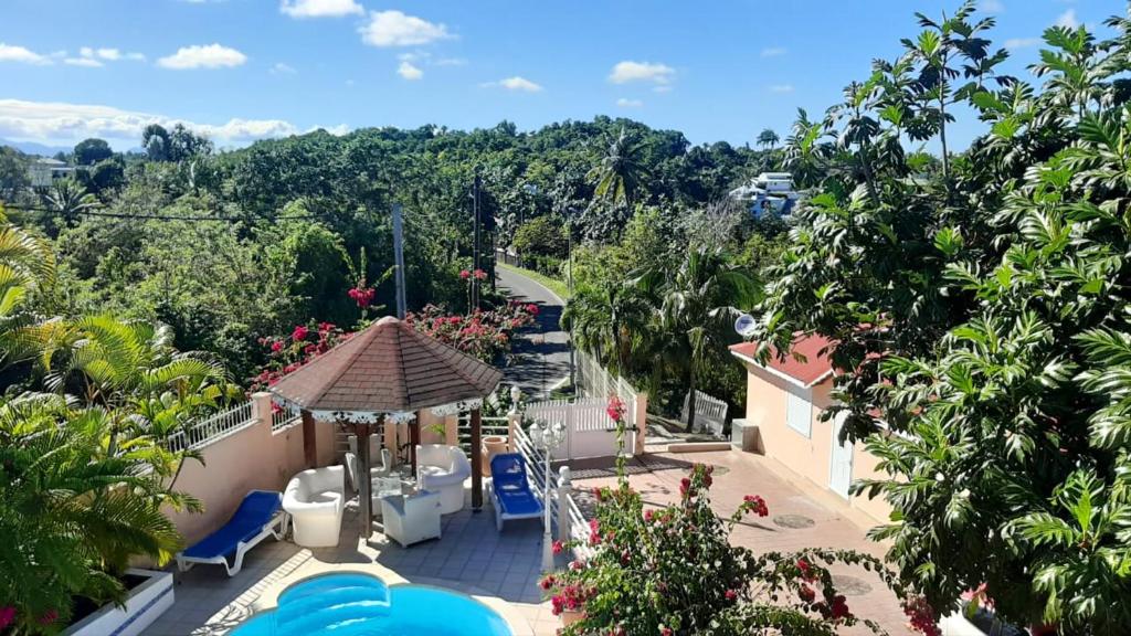 desde el balcón de una casa con sillas azules y árboles en Appartement d'une chambre avec piscine partagee balcon et wifi a Sainte Anne a 6 km de la plage, en Le Moule