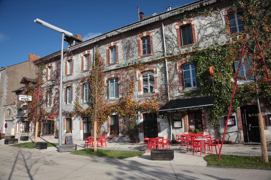 a building with red tables and chairs in front of it at Cit'Hotel Marie Stuart in La Roche-sur-Yon