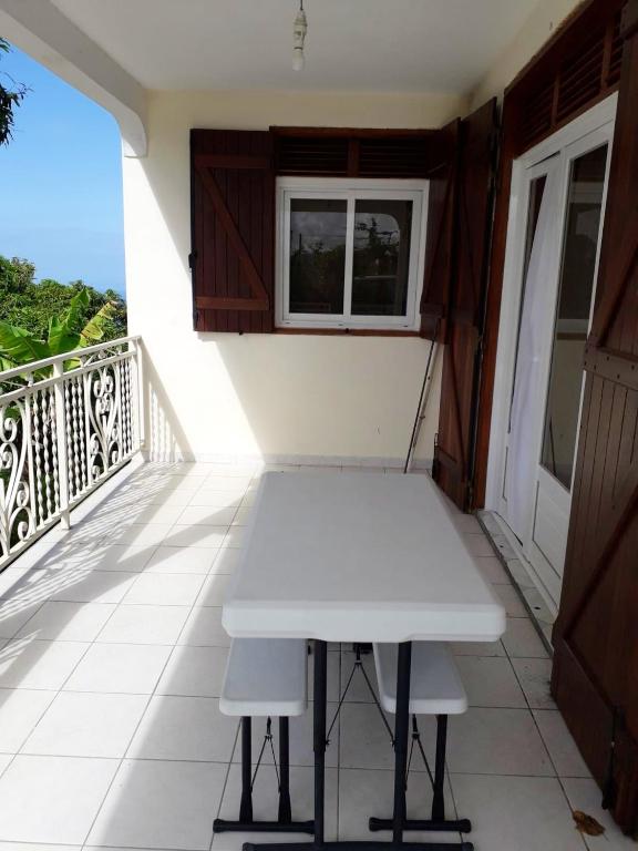 a white table on the balcony of a house at Maison de 3 chambres avec vue sur la mer terrasse et wifi a Vieux Habitants in Vieux-Habitants