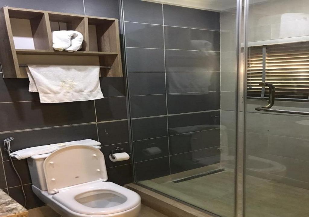 a bathroom with a toilet and a glass shower at Lit Suites in Abuja