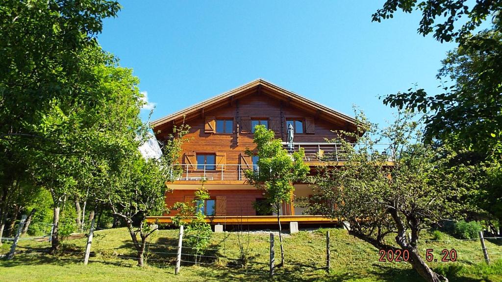 uma grande casa de madeira numa colina com árvores em Chambre d'Hôtes Barnabas em Saint-Martin-de-la-Porte