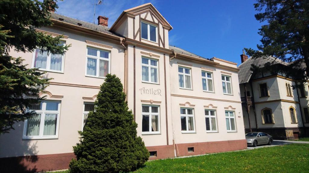 a building with a tree in front of it at Hotel Antler in Studénka