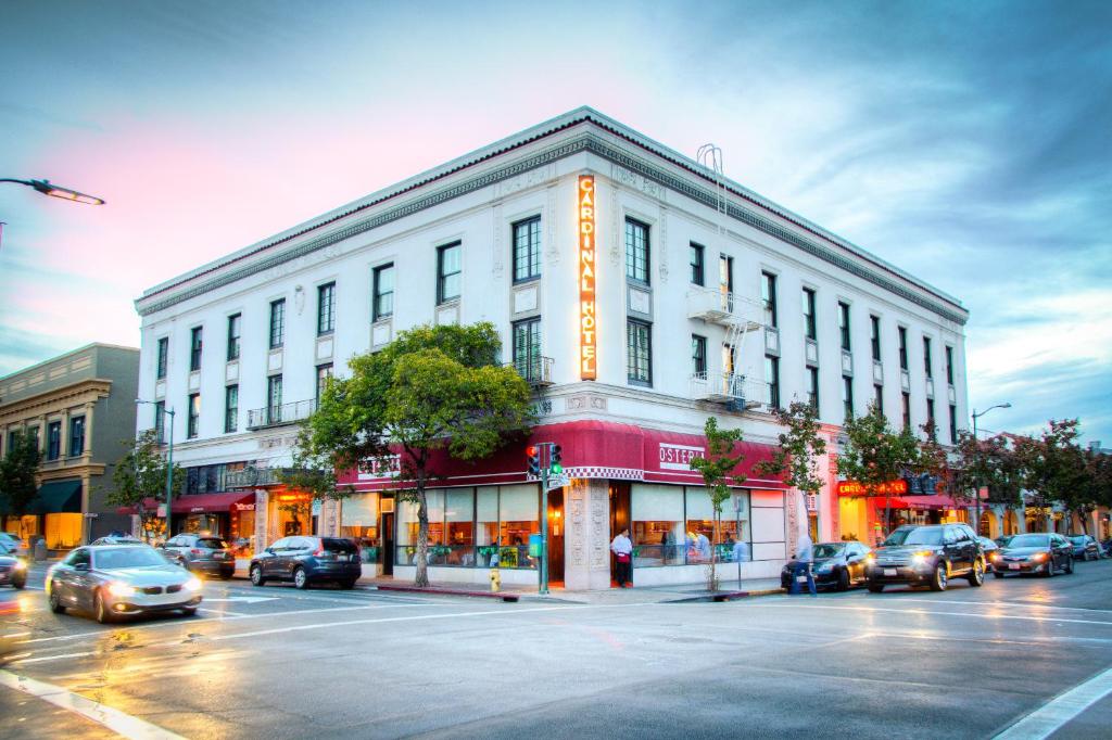 a large white building on a city street with cars at Cardinal Hotel in Palo Alto