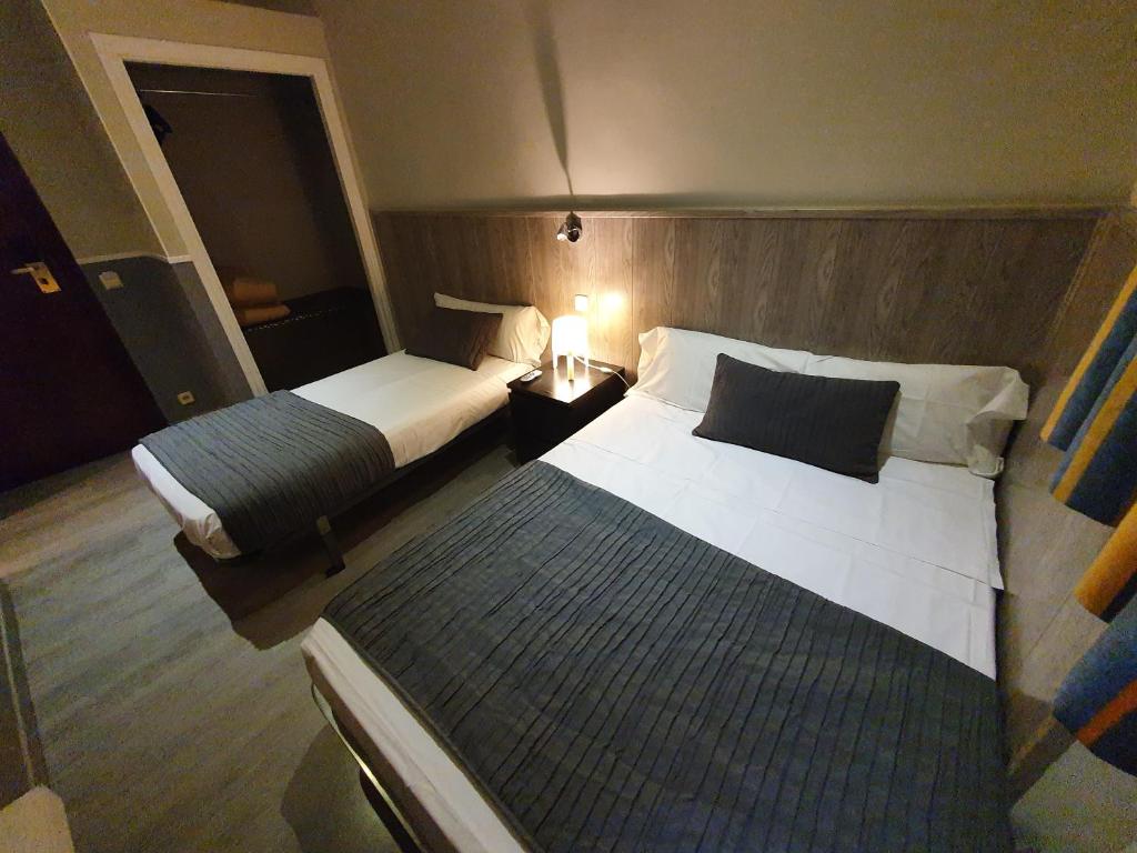 a hotel room with two beds and a night stand at CH Plaza D'Ort Rooms Madrid in Madrid