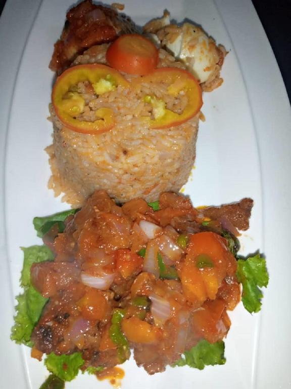a white plate topped with food with tomatoes and meat at Lit Suites in Abuja
