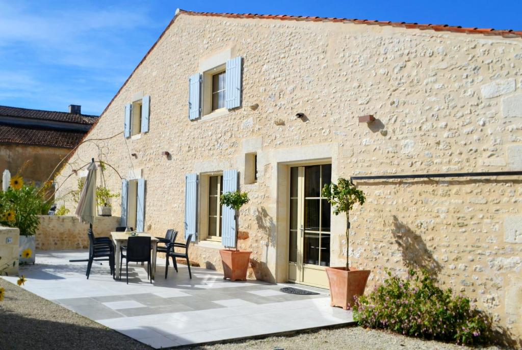 a patio with a table and chairs in front of a brick building at Maison spacieuse à Cabariot in Cabariot