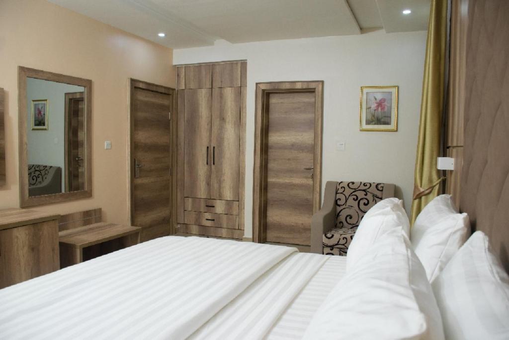 a bedroom with a large white bed and a mirror at Lit Suites in Abuja