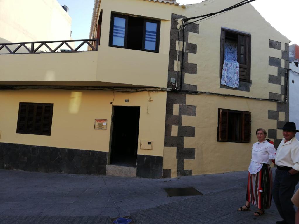 Un uomo e una donna in piedi davanti a un palazzo di Casa rural el Burro para grupos ad Agüimes