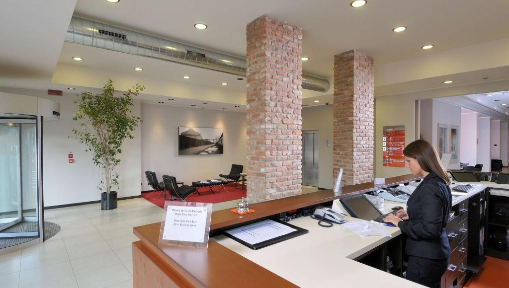 Kobieta stojąca przy kasie w salonie w obiekcie Best Western Falck Village Milano Sesto w mieście Sesto San Giovanni