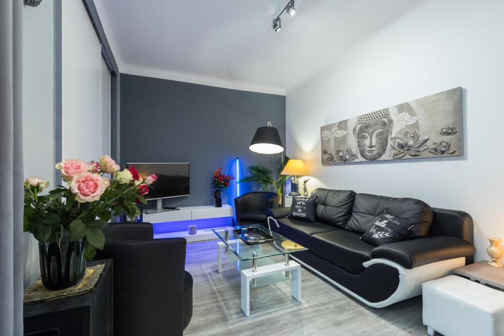 un salon avec un canapé noir et une télévision dans l'établissement Beau 3 pièces, 7 pers, 2 terrasses, centre, calme, sécurité, à Nice