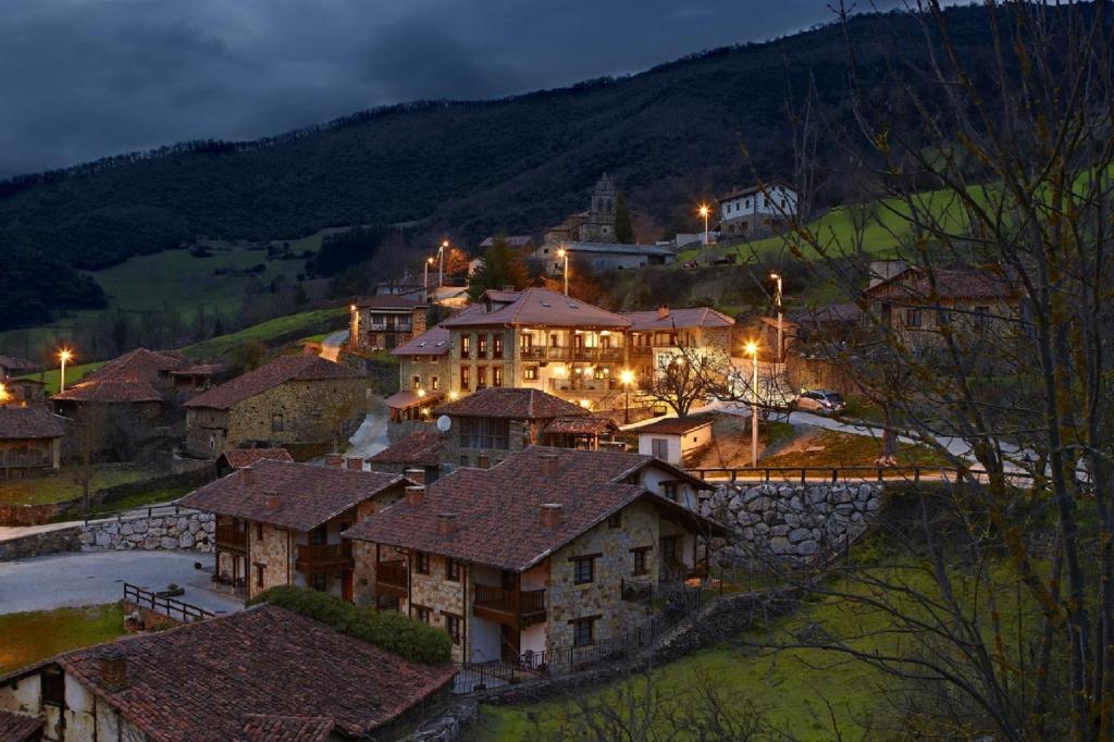 een groep huizen op een heuvel 's nachts bij Posada Valle del Oso in Lerones