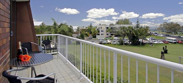 拜倫灣的住宿－主海灘公寓，一个带桌椅的阳台和一个停车位