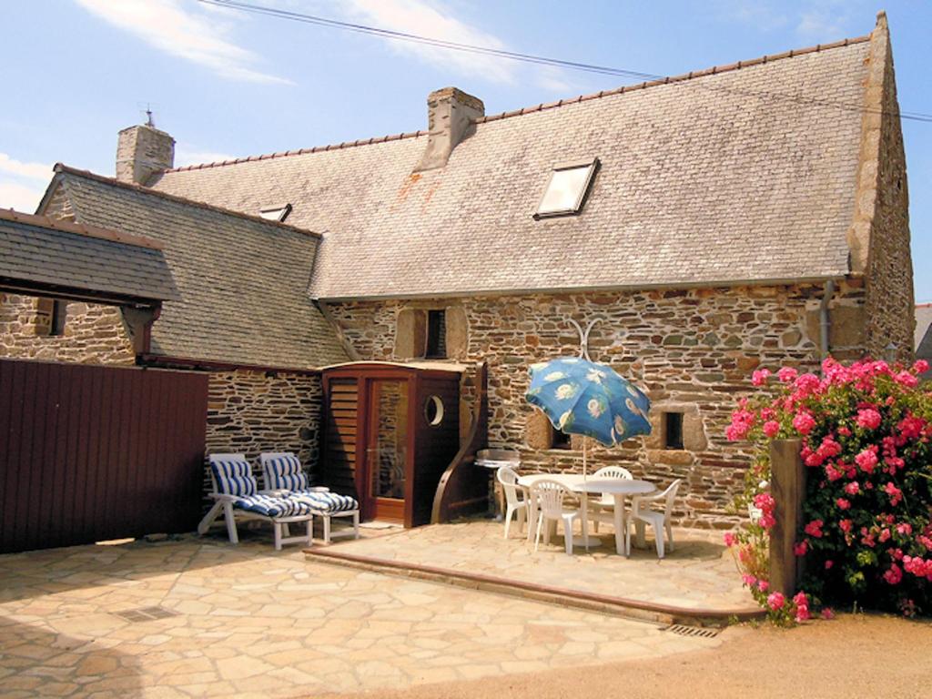 Cette maison en briques dispose d'une terrasse avec une table et des chaises. dans l'établissement Maison charmante à Trédrez-Locquémeau avec jardin et terrasse, à Trédrez