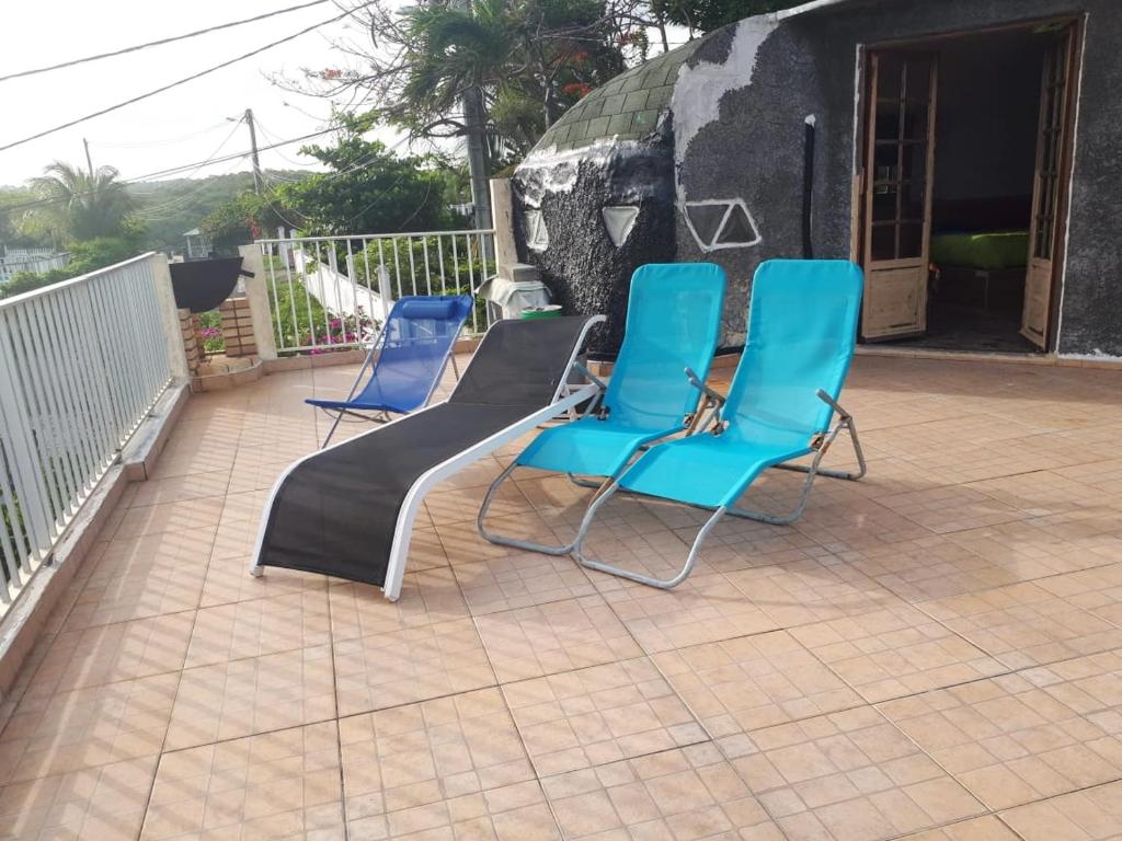 three chairs and a bench on a patio at Maison de 2 chambres a Sainte Anne a 100 m de la plage avec vue sur la mer jardin clos et wifi in Sainte-Anne