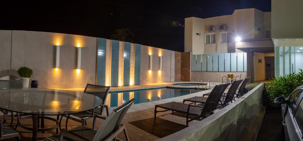 Mara Turismo Hotel في كاتالاو: فناء مع طاولة وكراسي بجوار حمام سباحة