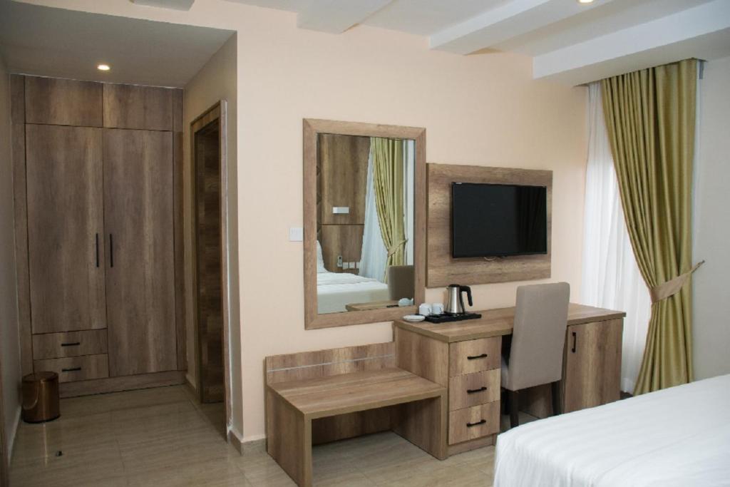a bedroom with a bed and a desk and a television at Lit Suites in Abuja